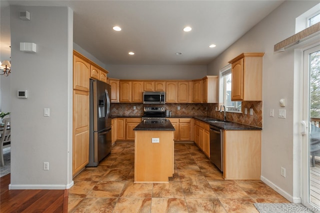 kitchen with appliances with stainless steel finishes, a sink, backsplash, and a kitchen island