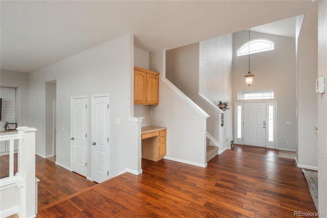 foyer with stairs, a high ceiling, dark wood finished floors, and baseboards