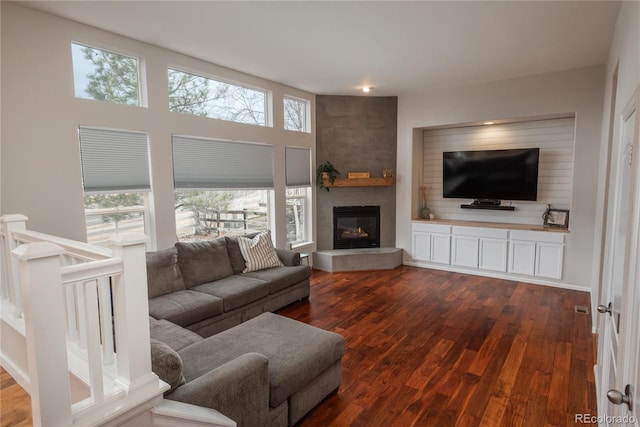 living room with dark wood-type flooring and a large fireplace