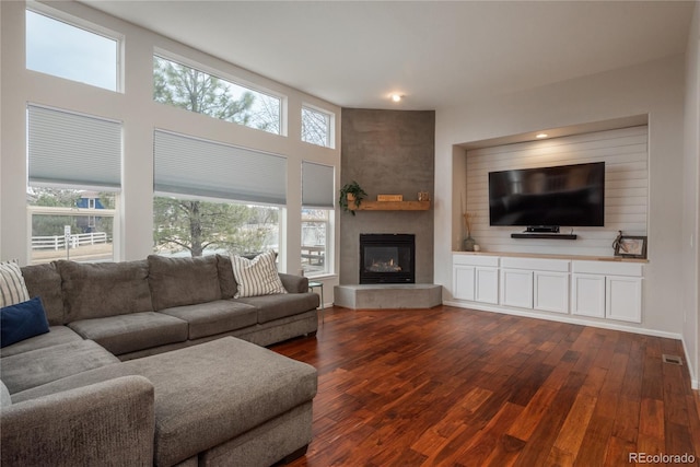 living area with dark wood-style floors, a large fireplace, and visible vents