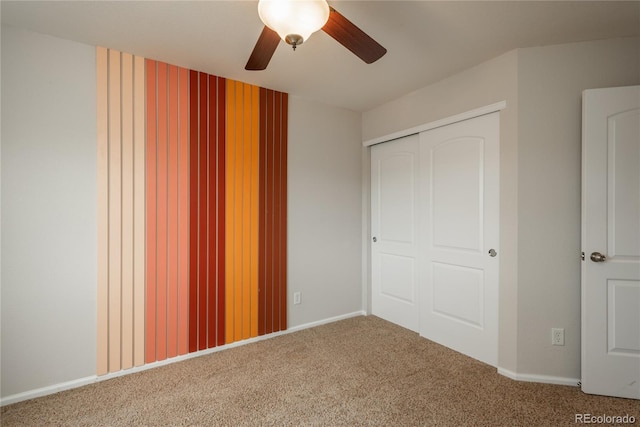 unfurnished bedroom featuring carpet, baseboards, ceiling fan, and a closet