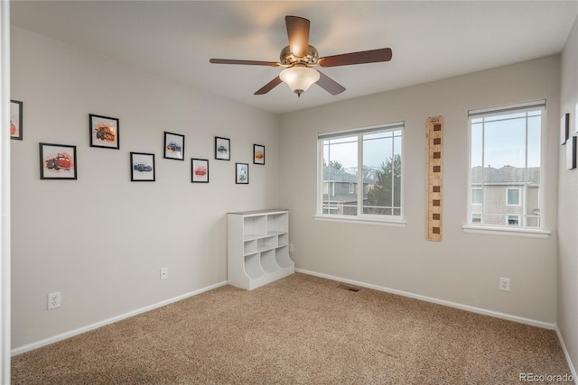 carpeted spare room with visible vents, ceiling fan, and baseboards