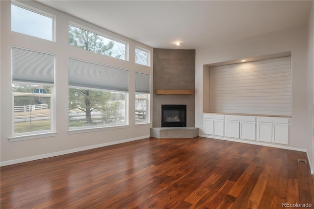 unfurnished living room with baseboards, dark wood finished floors, a fireplace, and visible vents
