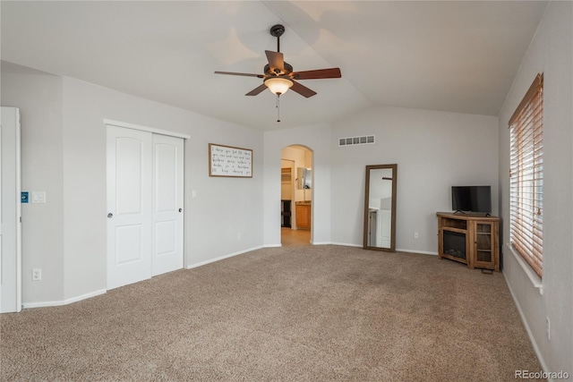 unfurnished living room with visible vents, vaulted ceiling, ceiling fan, arched walkways, and carpet floors