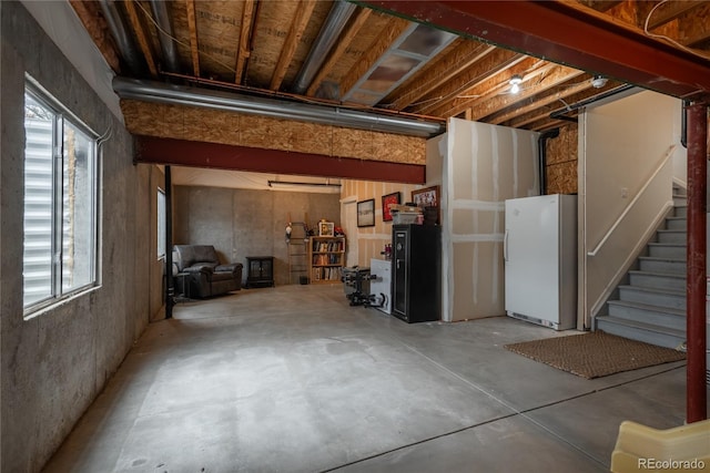 below grade area featuring freestanding refrigerator and stairs