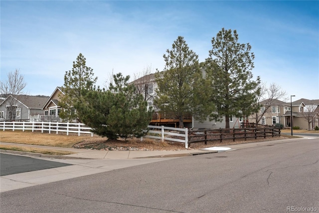 view of property hidden behind natural elements with a residential view and fence