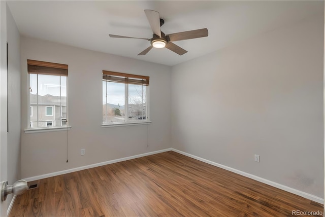 empty room featuring baseboards, visible vents, ceiling fan, and wood finished floors