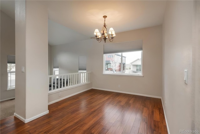 unfurnished room featuring a chandelier, a healthy amount of sunlight, and hardwood / wood-style flooring