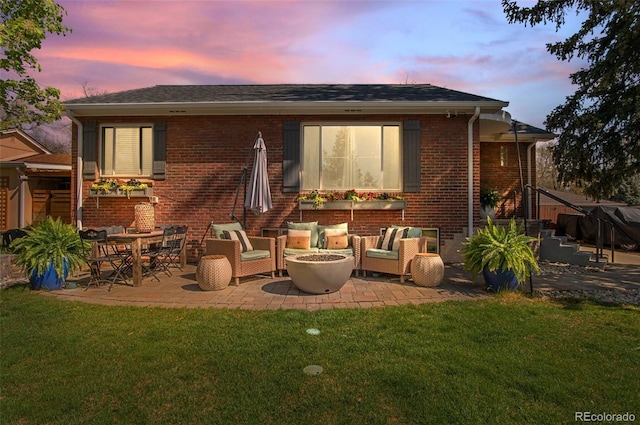 back of house with an outdoor living space with a fire pit, a patio, roof with shingles, brick siding, and a lawn