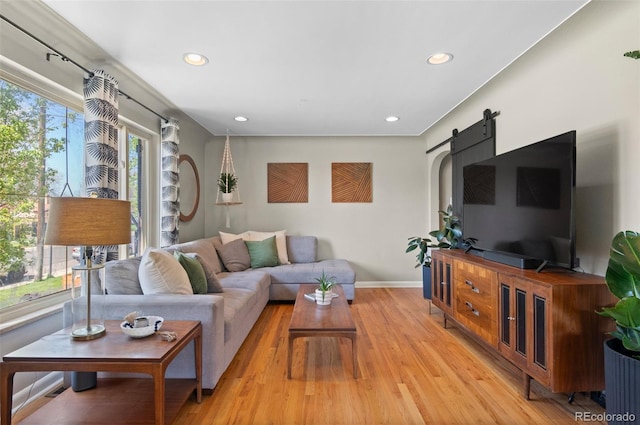 living room featuring light wood-style floors, a barn door, baseboards, and recessed lighting