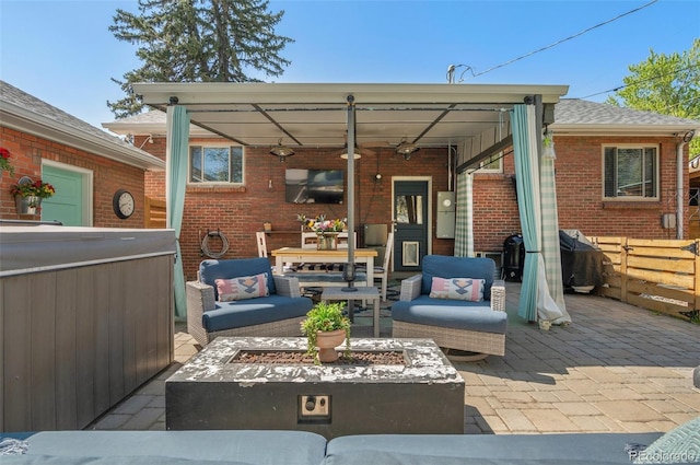 view of patio / terrace with a hot tub, ceiling fan, grilling area, and an outdoor living space with a fire pit