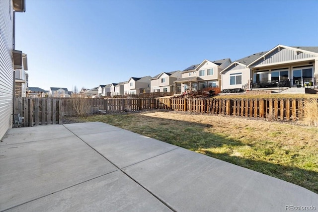 view of yard featuring a patio area, a fenced backyard, and a residential view