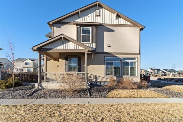 view of front of house featuring covered porch, board and batten siding, and fence