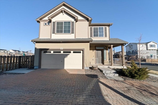 view of front facade featuring covered porch, decorative driveway, an attached garage, and fence