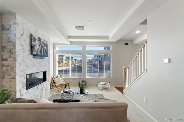 living area with carpet, visible vents, a fireplace, and baseboards