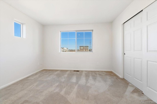 unfurnished bedroom with a closet, carpet flooring, visible vents, and baseboards