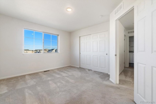 unfurnished bedroom with carpet floors, visible vents, and a closet