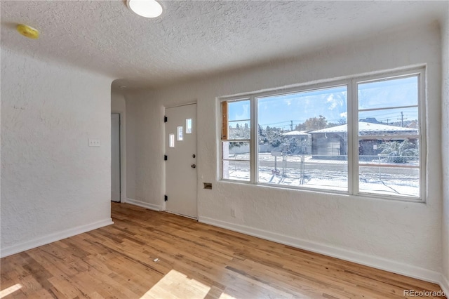 entryway with light hardwood / wood-style floors and a textured ceiling