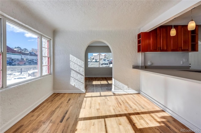 kitchen with light hardwood / wood-style flooring, hanging light fixtures, and a textured ceiling