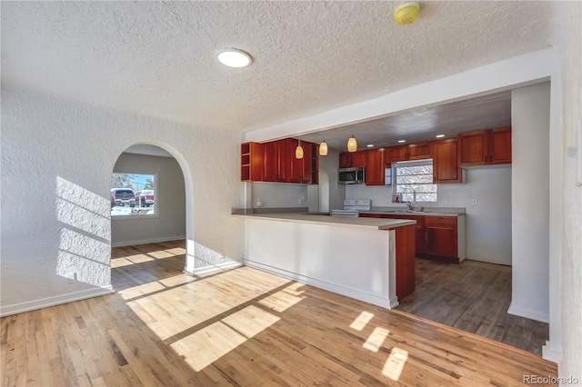 kitchen with hanging light fixtures, kitchen peninsula, wood-type flooring, and white electric stove