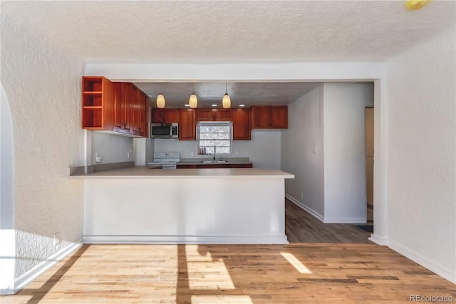 kitchen featuring kitchen peninsula, light hardwood / wood-style flooring, hanging light fixtures, a textured ceiling, and white range