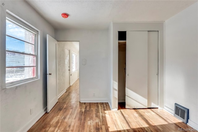 unfurnished bedroom with a closet, hardwood / wood-style floors, and a textured ceiling