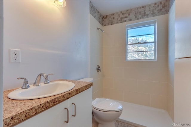 bathroom featuring tile patterned floors, vanity, toilet, and tiled shower