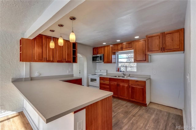 kitchen featuring light wood-type flooring, kitchen peninsula, decorative light fixtures, and electric range