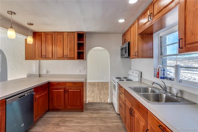 kitchen featuring stainless steel appliances, hanging light fixtures, sink, and light wood-type flooring