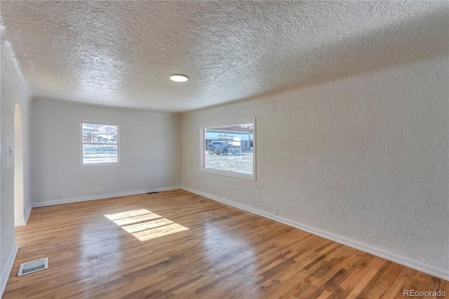 spare room featuring light wood-type flooring and a textured ceiling