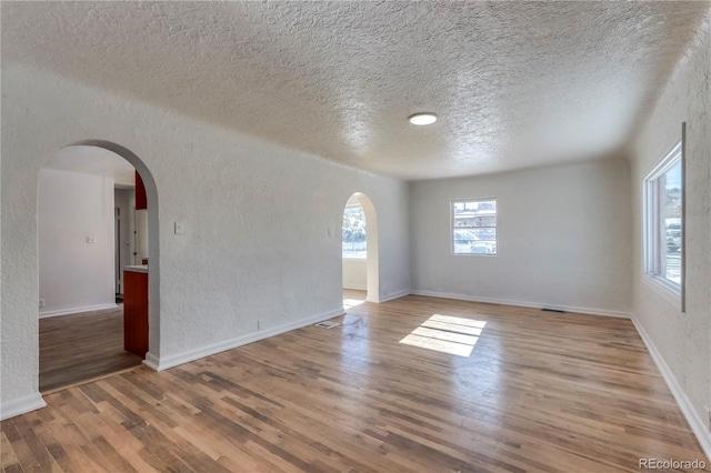 empty room with a textured ceiling and light wood-type flooring