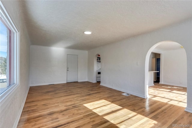 spare room with a textured ceiling and light hardwood / wood-style flooring