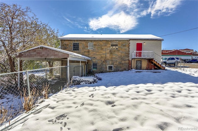 snow covered back of property featuring a carport