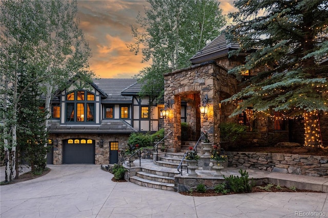 view of front of home with concrete driveway, an attached garage, and stone siding