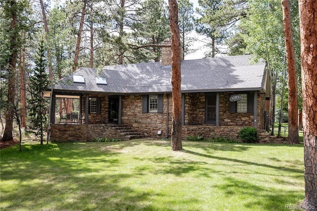 view of front of property with a front lawn, a chimney, stone siding, and a shingled roof