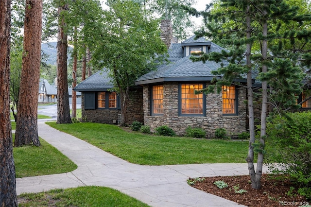 view of front of property featuring a chimney, a front lawn, and a shingled roof