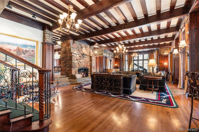 living room featuring stairs, hardwood / wood-style flooring, a notable chandelier, and decorative columns