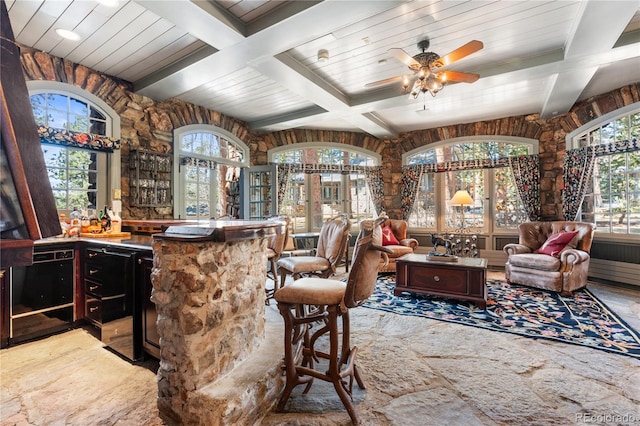 bar featuring beam ceiling, coffered ceiling, indoor bar, wood ceiling, and ceiling fan