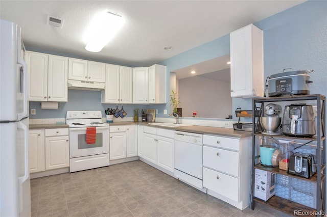 kitchen featuring visible vents, under cabinet range hood, white cabinets, white appliances, and a sink