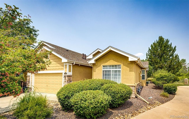 view of front of property featuring stone siding, stucco siding, driveway, and an attached garage