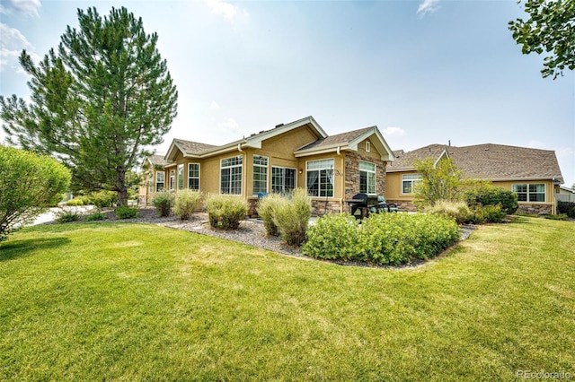 back of property featuring stone siding, a lawn, and stucco siding