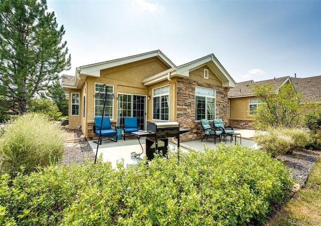 back of house featuring stone siding, stucco siding, and a patio