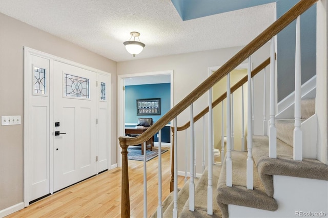 foyer entrance featuring a textured ceiling and light hardwood / wood-style flooring