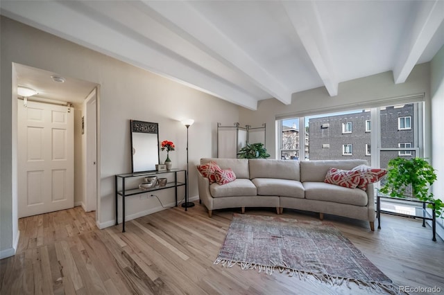 living area featuring beamed ceiling, baseboards, and light wood-type flooring