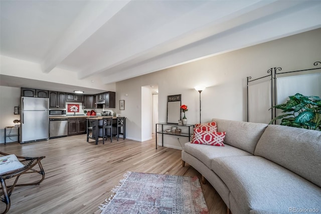 living room with beamed ceiling, baseboards, and light wood finished floors