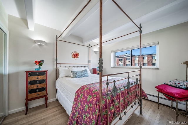 bedroom featuring a baseboard heating unit, baseboards, and wood finished floors