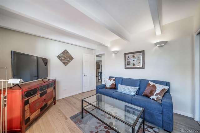 living area featuring baseboards, beam ceiling, and wood finished floors