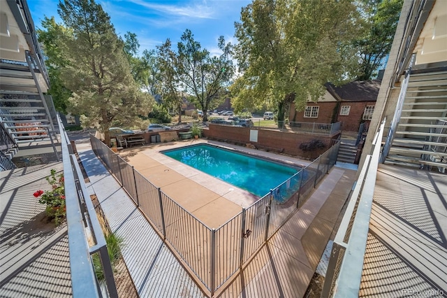 view of swimming pool with stairs and fence