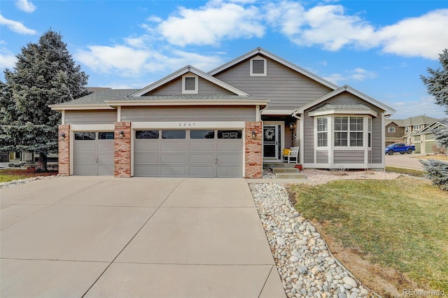 view of front of property featuring an attached garage, driveway, a front yard, and brick siding