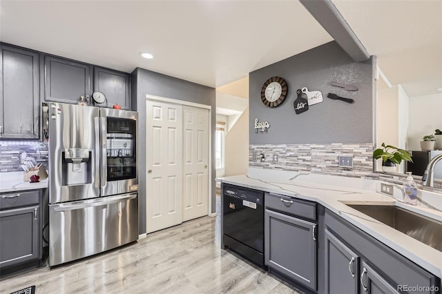 kitchen with gray cabinetry, a sink, light wood-style floors, stainless steel fridge with ice dispenser, and dishwasher